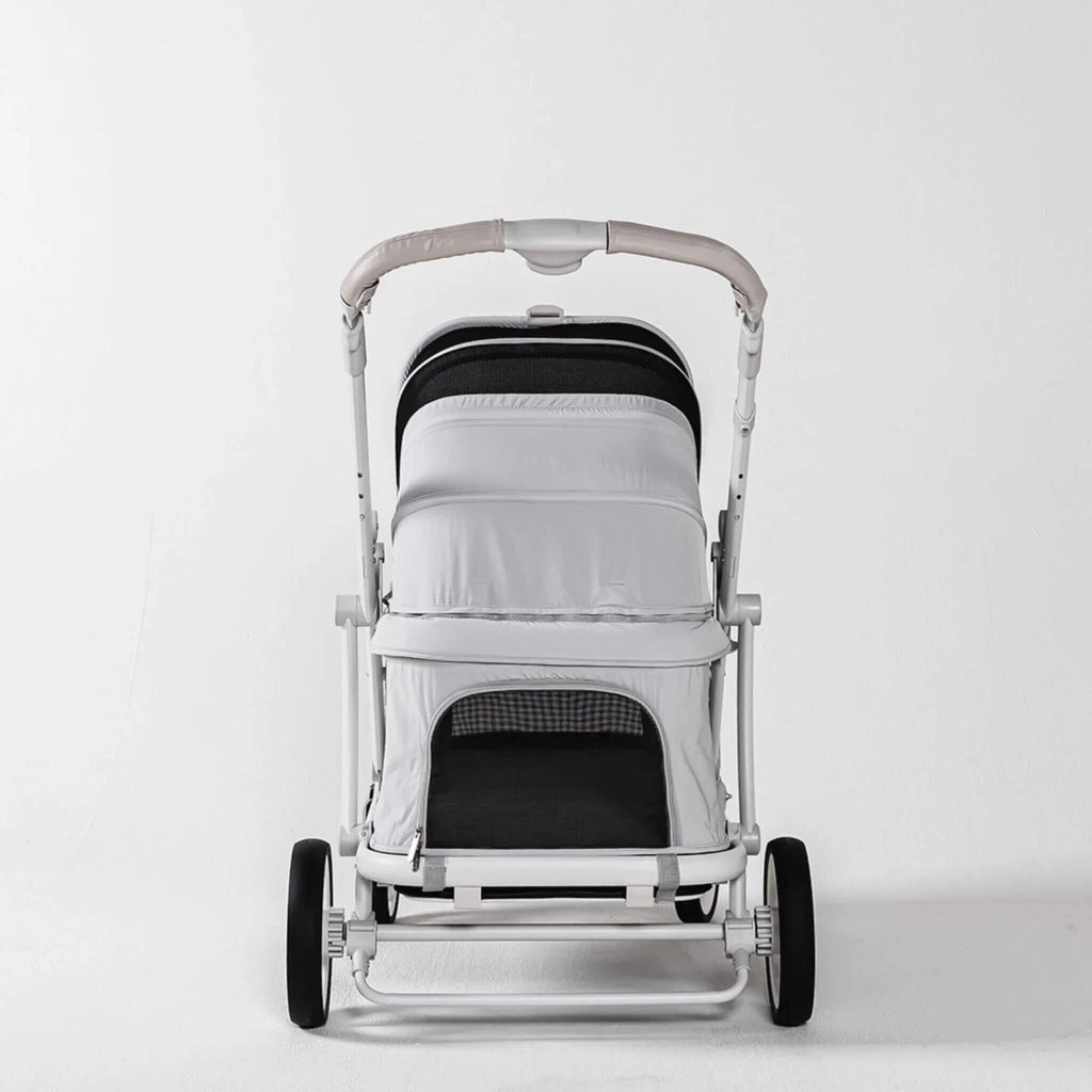 A modern pet stroller with a white and black canopy, a light gray padded seat cover, and a white frame with black wheels, photographed against a seamless white studio background.