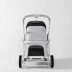 A modern pet stroller with a white and black canopy, a light gray padded seat cover, and a white frame with black wheels, photographed against a seamless white studio background.