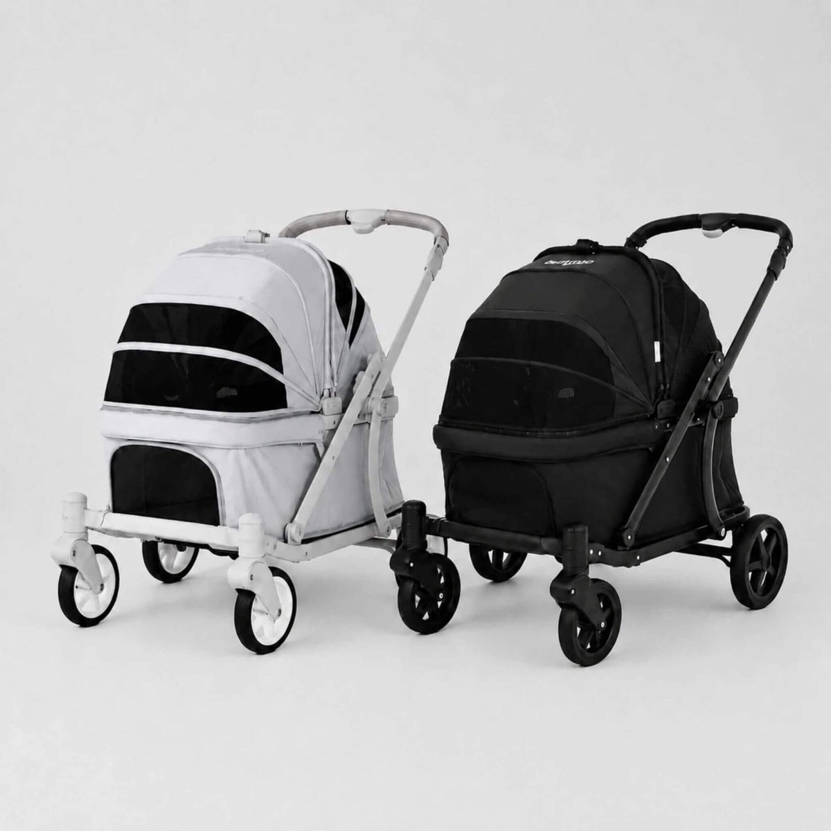 Two pet strollers shown side by side on a light gray studio background. The stroller on the left is white with black panels, and the stroller on the right is black with black panels.